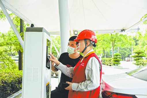 国网重庆电力员工在铜梁新城充电站向车主介绍充电桩功能。